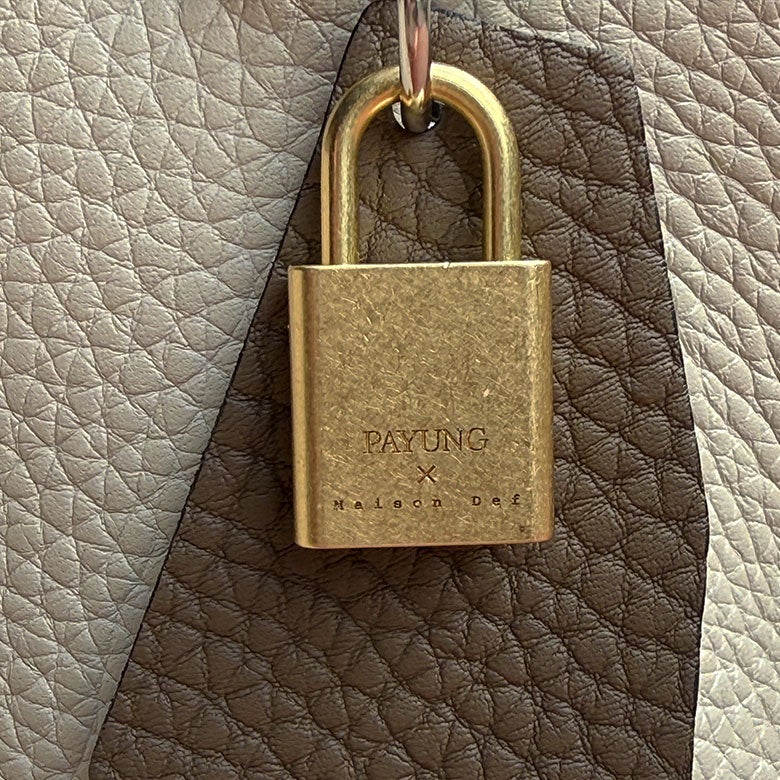 ダブルネーム刻印の錠前とアシンメトリーデザインのレザー